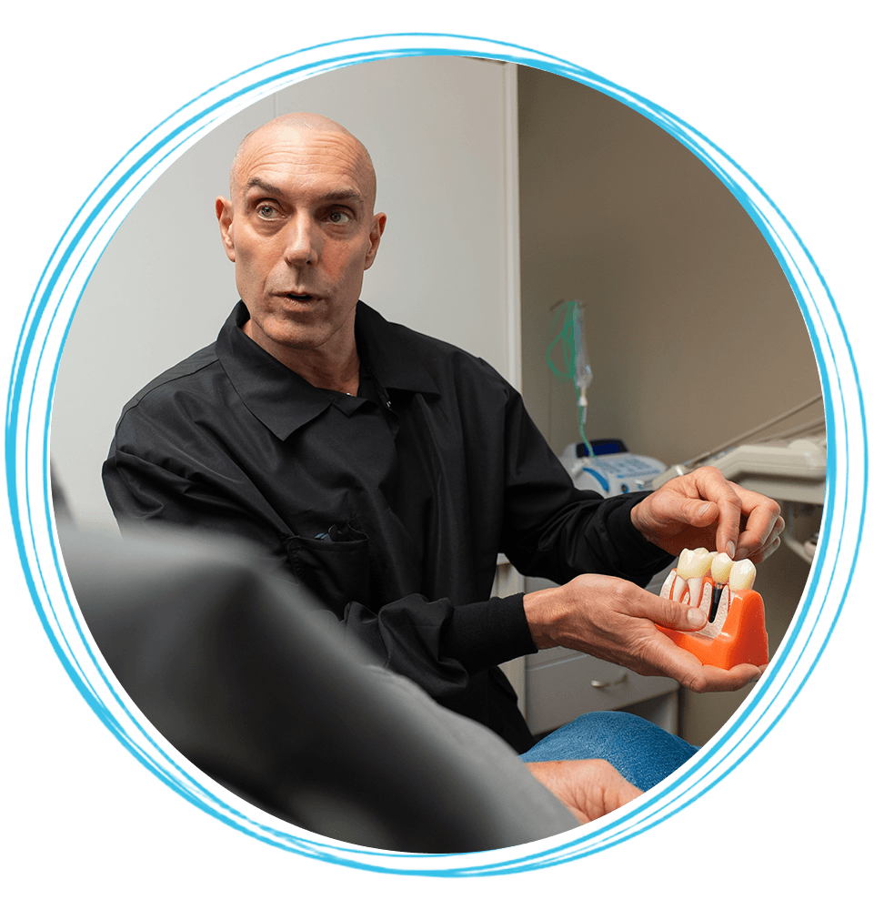dr pointing to real dental implant model